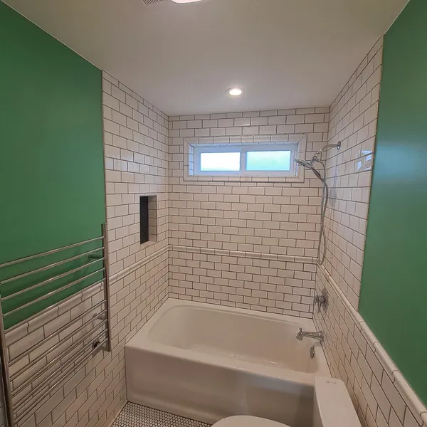 Tub and shower with a white subway-tile surround, a built-in niche and a frosted window