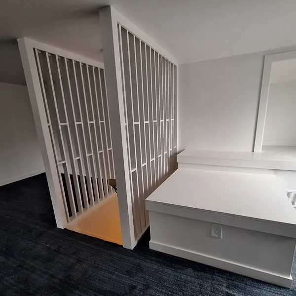 Finished attic bedroom with navy carpet, a white slat partition at the stair and a built-in bench