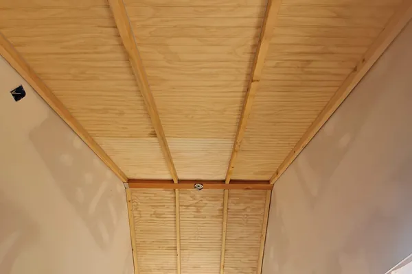 Finished beadboard ceiling over the covered deck with the stained beams running to the walls