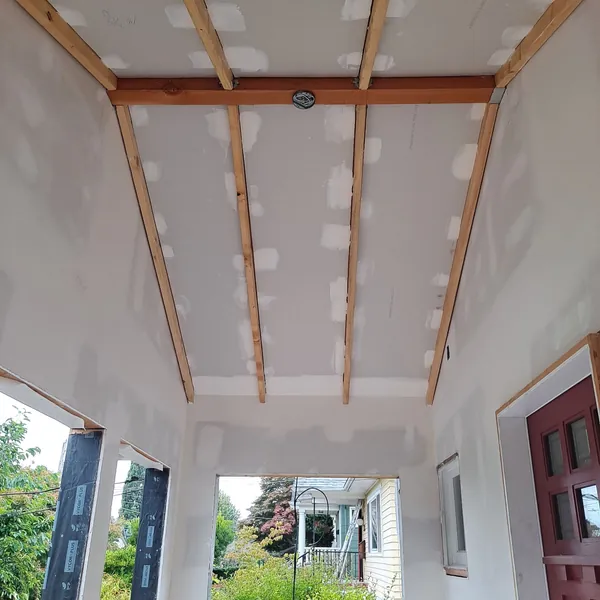 Covered deck ceiling in taped drywall with exposed joists before finishing